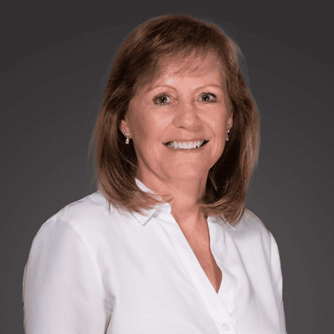 Smiling woman in a white blouse against a gray background.
