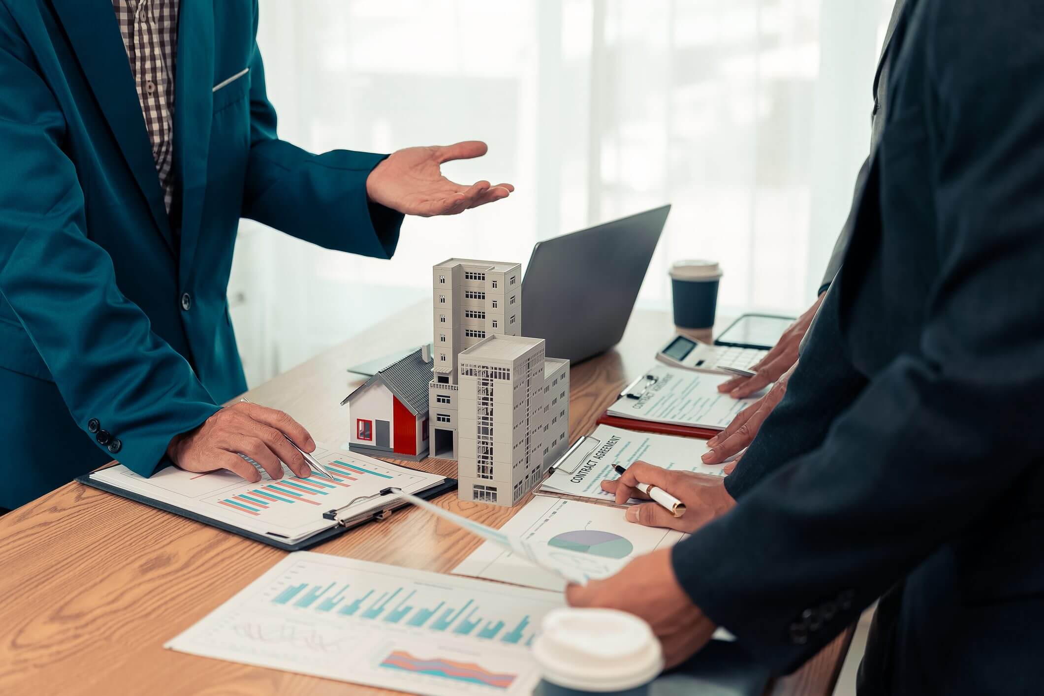 Business meeting with architectural models on table.