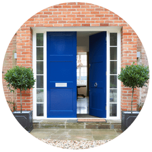 Blue front door on a brick house with two potted plants.
