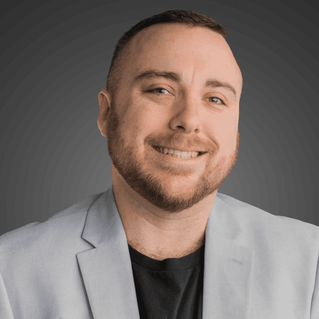 Smiling man in light gray blazer with dark shirt.